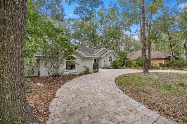 ranch-style home featuring stucco siding and curved driveway