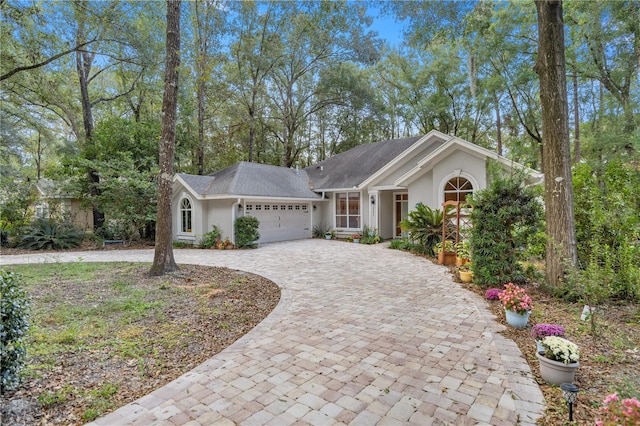 view of front of property with stucco siding, decorative driveway, an attached garage, and a shingled roof