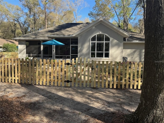 view of property exterior featuring fence, a sunroom, and stucco siding