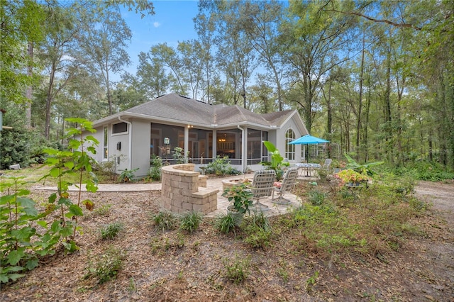 back of house featuring a patio area, stucco siding, a shingled roof, and a sunroom