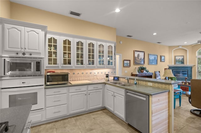 kitchen featuring a peninsula, a glass covered fireplace, visible vents, a sink, and stainless steel appliances