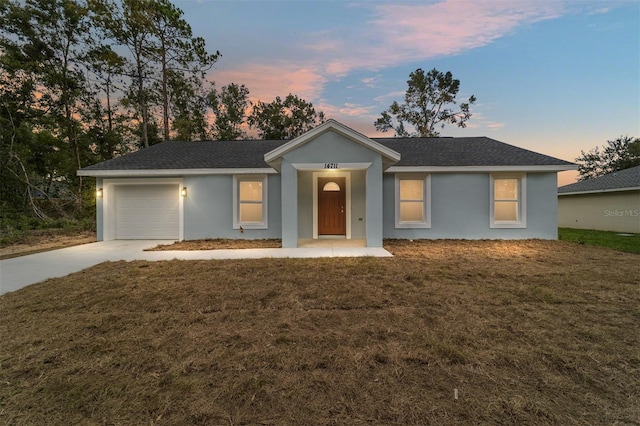 ranch-style home featuring a garage and a lawn