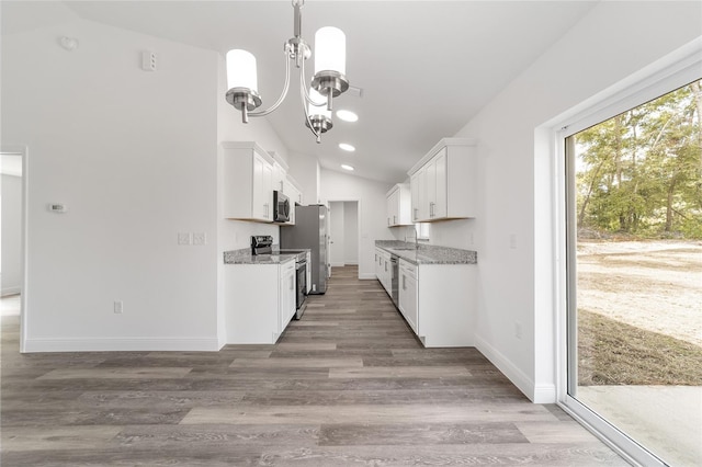 kitchen with light stone countertops, vaulted ceiling, white cabinetry, and stainless steel appliances