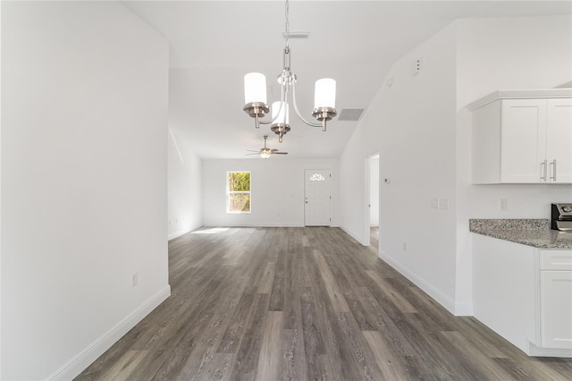 unfurnished dining area featuring ceiling fan with notable chandelier, vaulted ceiling, and dark hardwood / wood-style floors