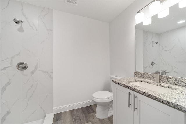 bathroom featuring vanity, toilet, tiled shower, and hardwood / wood-style floors