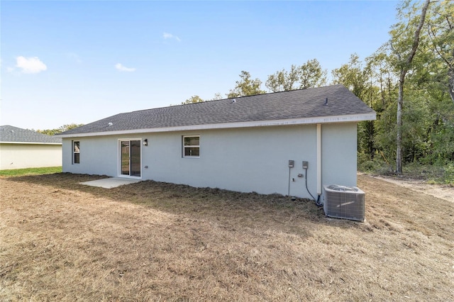 rear view of house featuring a lawn and central AC unit