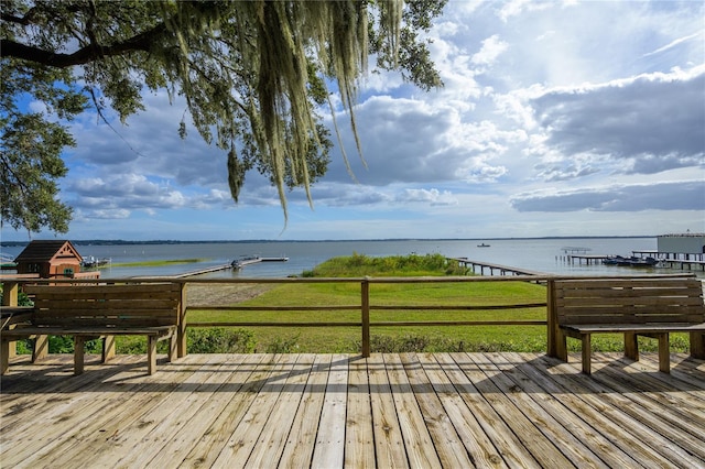 wooden deck featuring a water view and a lawn