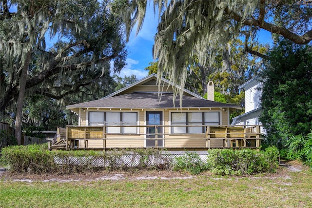 back of property featuring a deck and a lawn