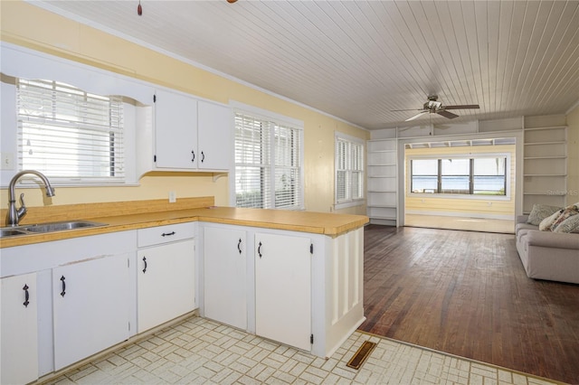 kitchen with sink, kitchen peninsula, white cabinetry, light hardwood / wood-style floors, and ceiling fan