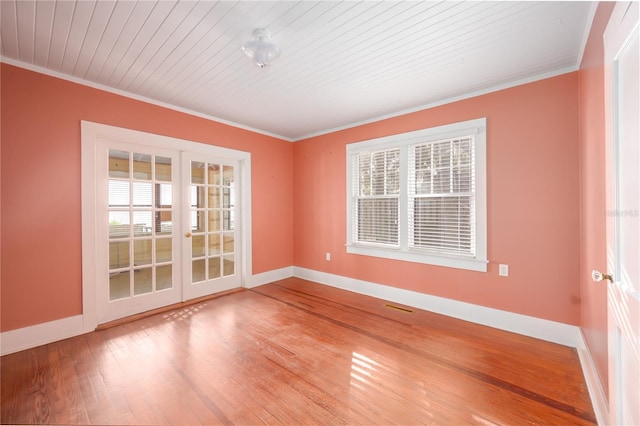 empty room featuring french doors, wood ceiling, ornamental molding, and hardwood / wood-style floors