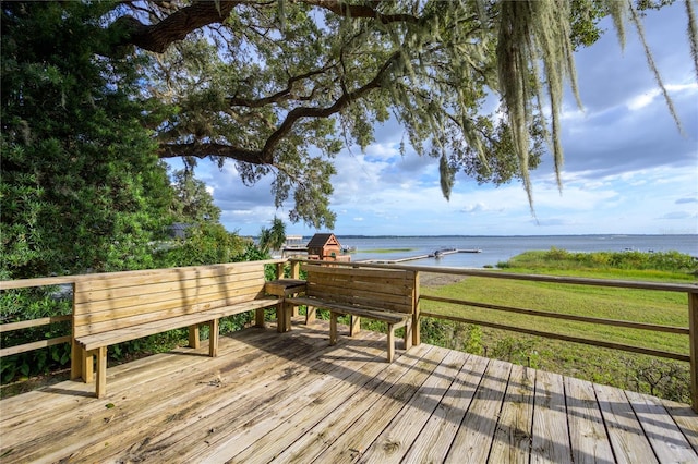 wooden terrace with a water view and a lawn