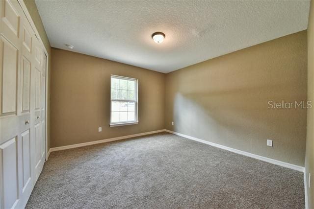 unfurnished bedroom with a closet, carpet, and a textured ceiling