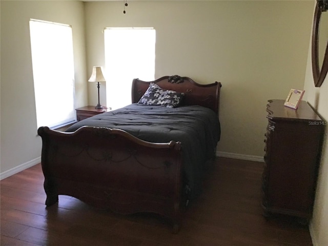 bedroom with multiple windows and dark hardwood / wood-style floors