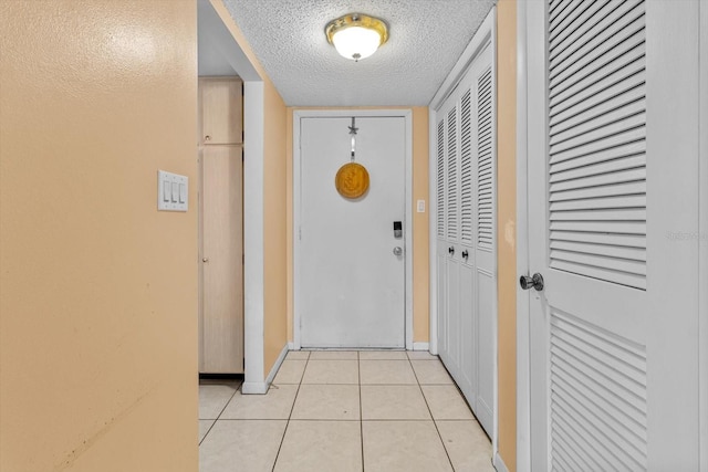 hall featuring a textured ceiling and light tile patterned floors