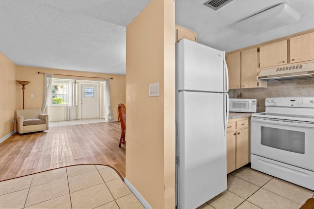 kitchen featuring light hardwood / wood-style floors, light brown cabinets, a textured ceiling, and white appliances