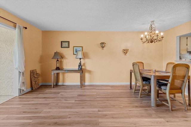 dining room featuring a chandelier, a textured ceiling, and light wood-type flooring