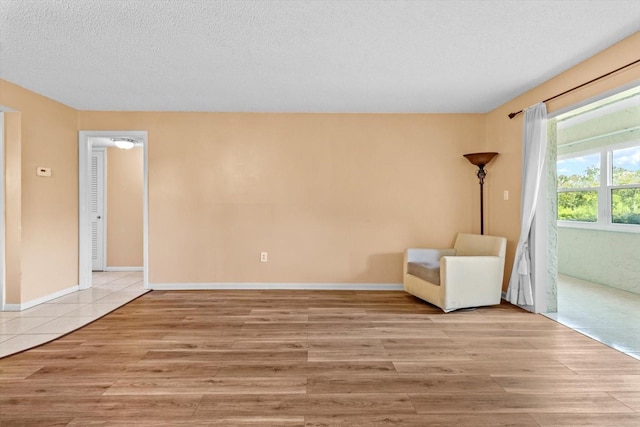 unfurnished room with a textured ceiling and light wood-type flooring