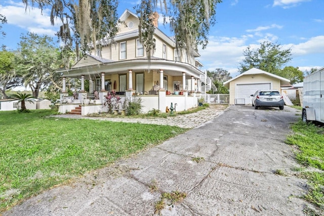 view of front of property featuring a front yard, a porch, an outbuilding, and a garage