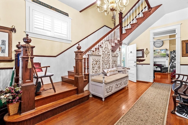 stairway with hardwood / wood-style floors and a chandelier