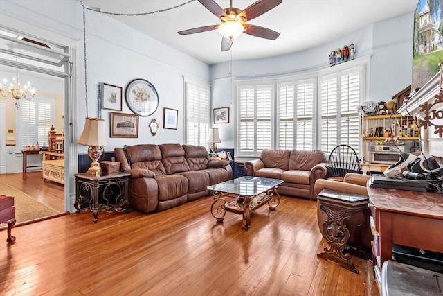 living room featuring hardwood / wood-style flooring and ceiling fan with notable chandelier