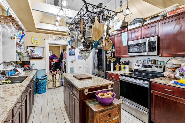 kitchen featuring appliances with stainless steel finishes, a center island, light stone countertops, and sink