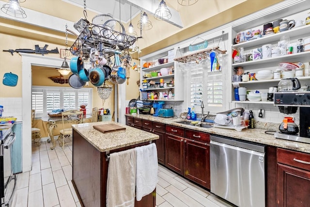 kitchen featuring light stone counters, backsplash, a kitchen island, sink, and stainless steel appliances