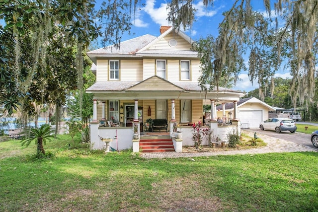 view of front of house featuring a porch, an outbuilding, a front lawn, and a garage