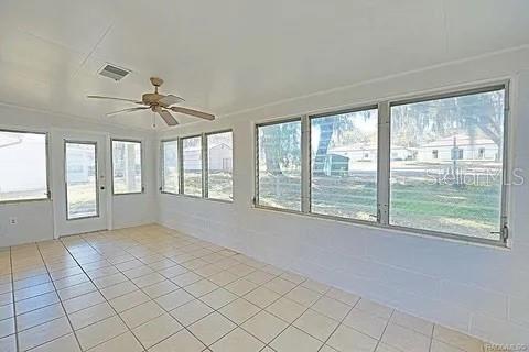 unfurnished sunroom featuring ceiling fan and a wealth of natural light