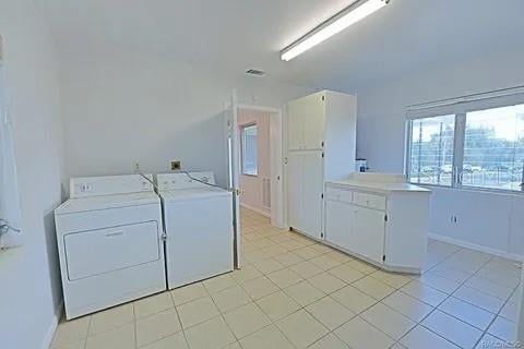 laundry area with cabinets, light tile patterned flooring, and washing machine and clothes dryer