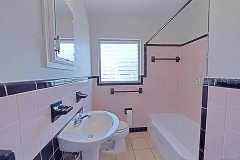 full bathroom with tile walls, tile patterned floors, shower / washtub combination, and toilet