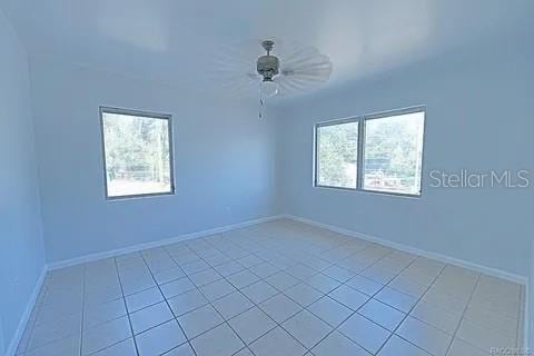 tiled spare room with ceiling fan