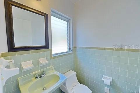 bathroom featuring toilet, tile walls, and plenty of natural light