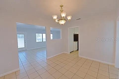 spare room featuring a notable chandelier and light tile patterned floors