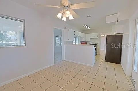 kitchen with appliances with stainless steel finishes, white cabinets, ceiling fan, and light tile patterned floors