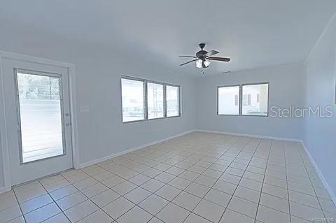 tiled spare room featuring ceiling fan and a wealth of natural light