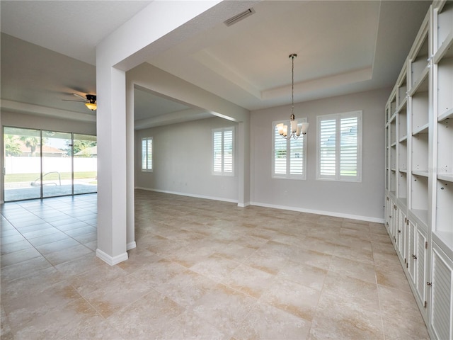 tiled spare room with ceiling fan with notable chandelier and a raised ceiling