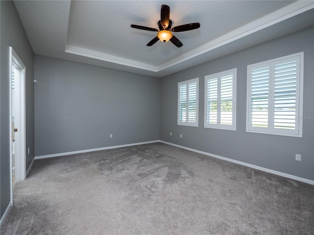 empty room with a textured ceiling, a raised ceiling, carpet floors, and ceiling fan