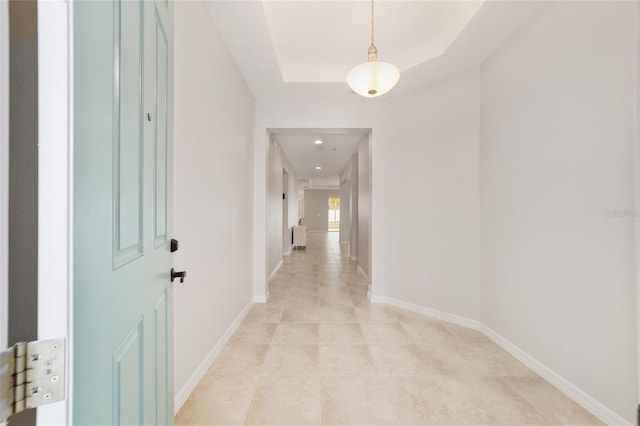 corridor featuring a raised ceiling and light tile patterned floors