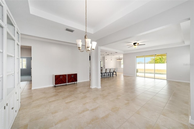 spare room with light tile patterned flooring, plenty of natural light, ceiling fan with notable chandelier, and a tray ceiling