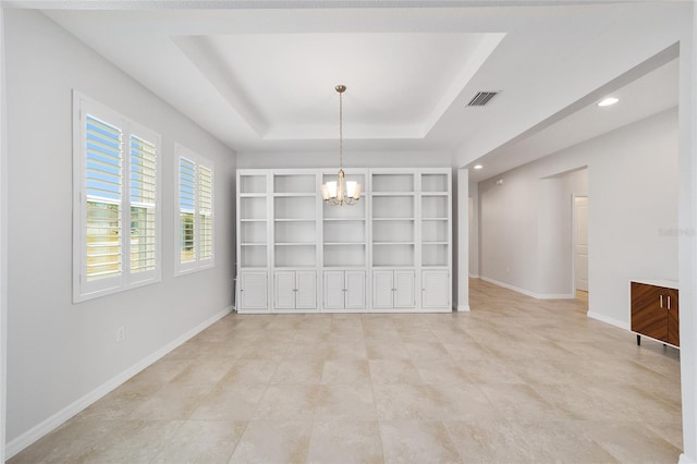 unfurnished dining area featuring an inviting chandelier and a tray ceiling