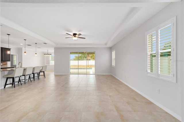 living room with light tile patterned floors, a raised ceiling, and ceiling fan