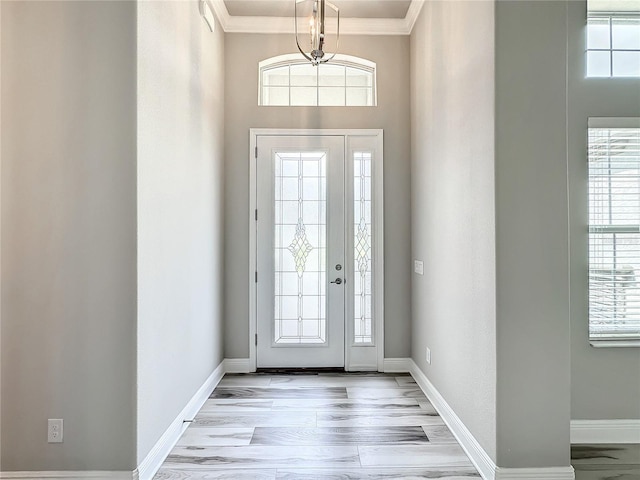 foyer featuring a healthy amount of sunlight, ornamental molding, and light hardwood / wood-style flooring