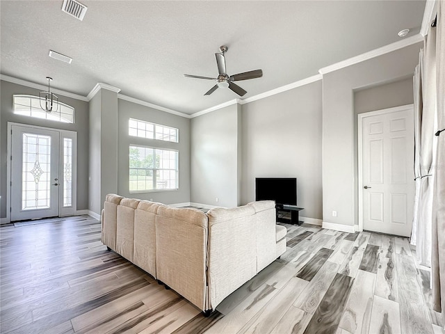 living room featuring ornamental molding, light hardwood / wood-style flooring, a textured ceiling, and ceiling fan