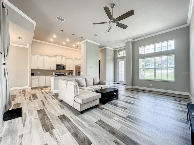 living room with ornamental molding, light wood-type flooring, and ceiling fan