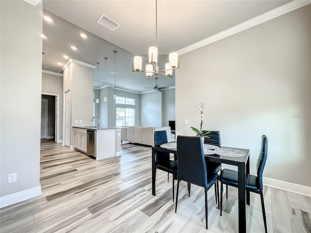 dining room with light hardwood / wood-style floors, crown molding, sink, and ceiling fan with notable chandelier