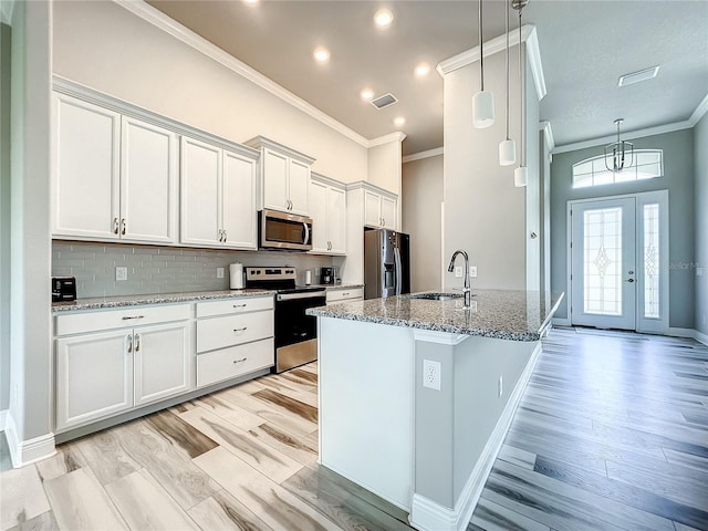 kitchen with white cabinetry, light stone countertops, appliances with stainless steel finishes, and decorative light fixtures