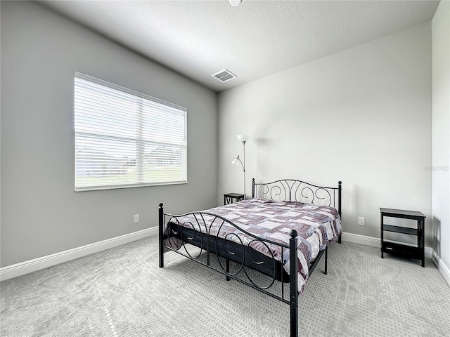 bedroom featuring a textured ceiling and light colored carpet