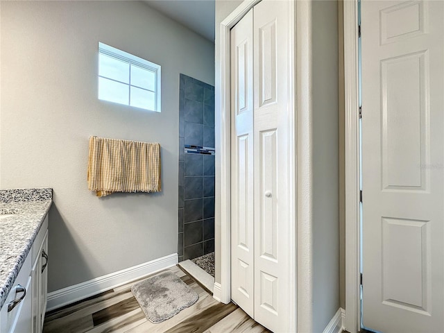 bathroom featuring vanity, hardwood / wood-style flooring, and tiled shower