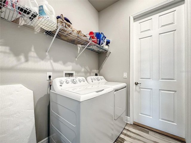 laundry area with light hardwood / wood-style flooring and washer and clothes dryer