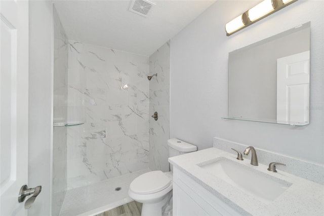 full bath with a marble finish shower, visible vents, toilet, wood finished floors, and vanity